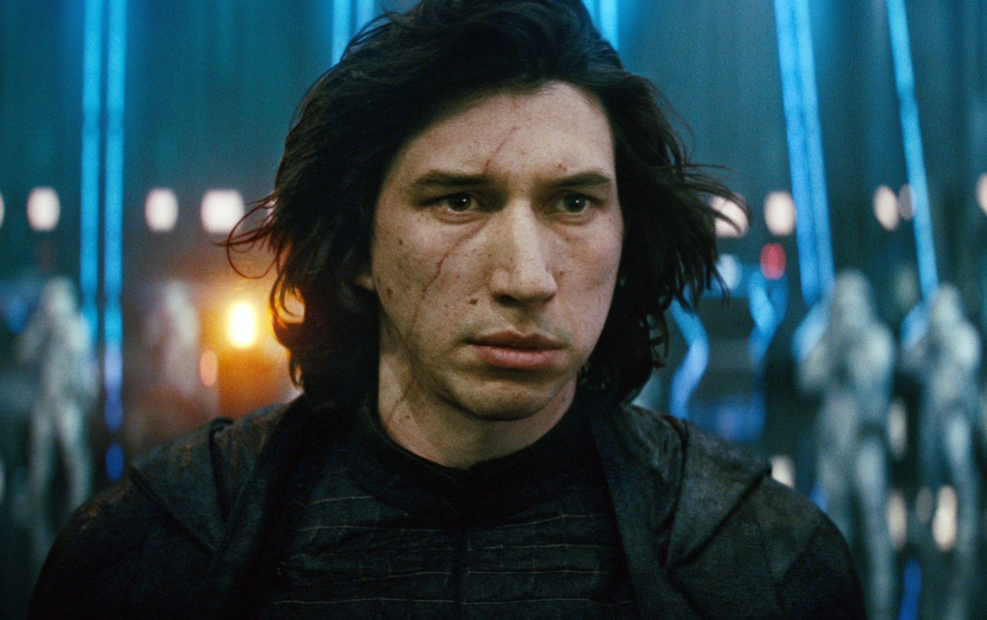 A character, wearing dark attire and looking intense, stands in a sci-fi setting with futuristic blue lighting and figures in the background