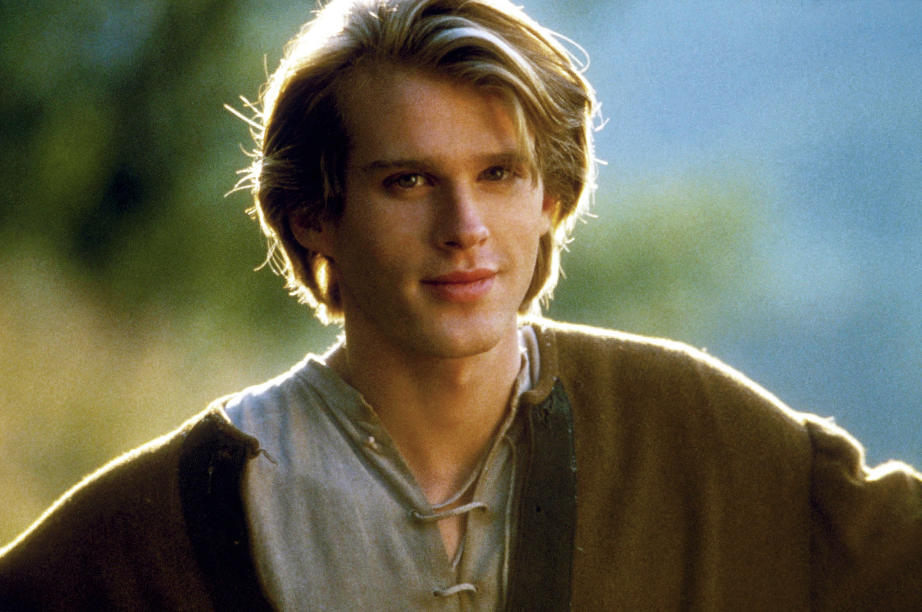 Person outdoors wearing medieval-style clothing with long sleeves and laced neckline, looking directly at the camera
