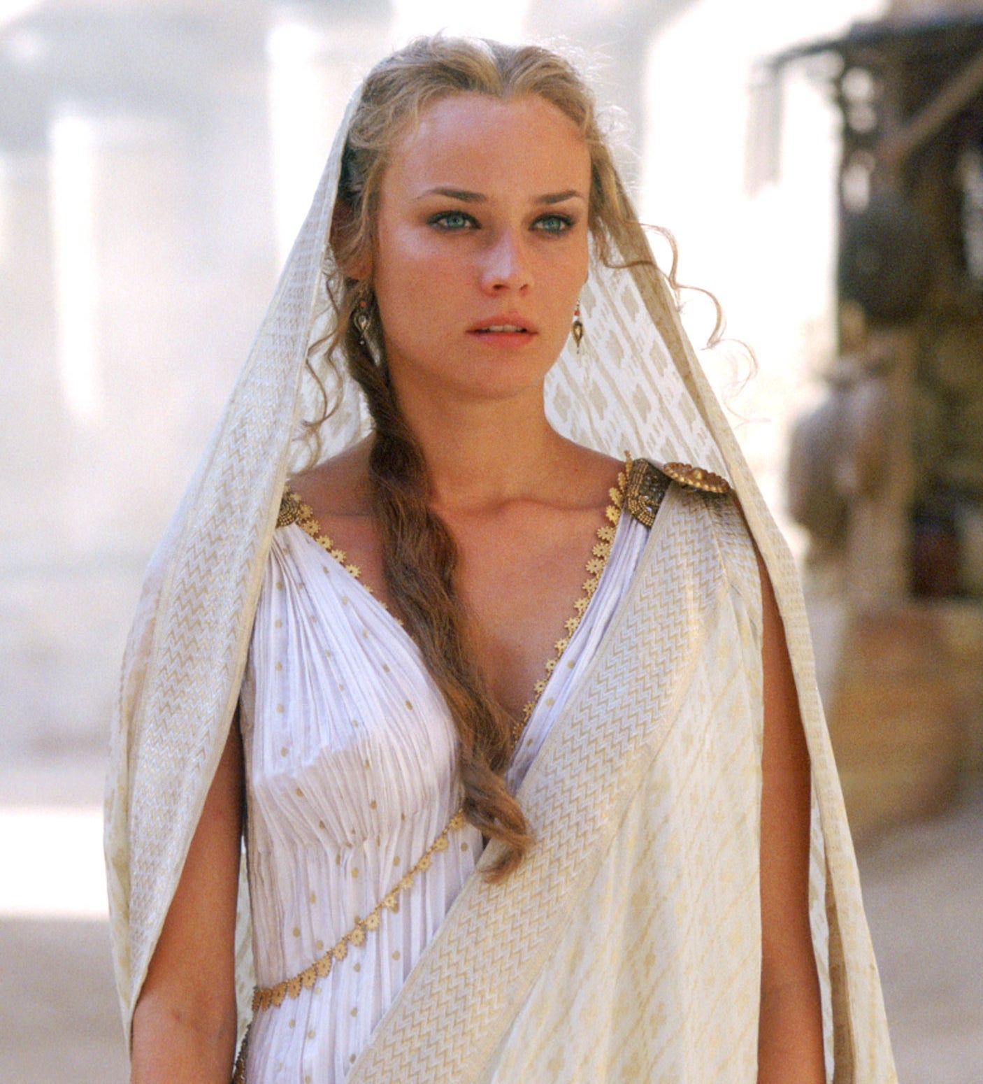 Person in an ancient-themed setting, wearing a draped, Greco-Roman style gown with braided hair, looking thoughtfully ahead