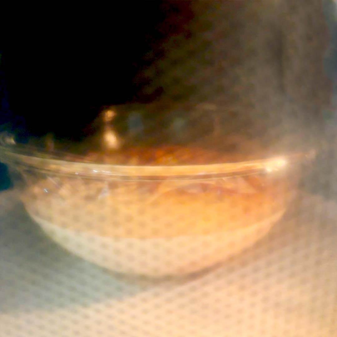 電子レンジの中で透明のボウルに入った食品が加熱されている様子。