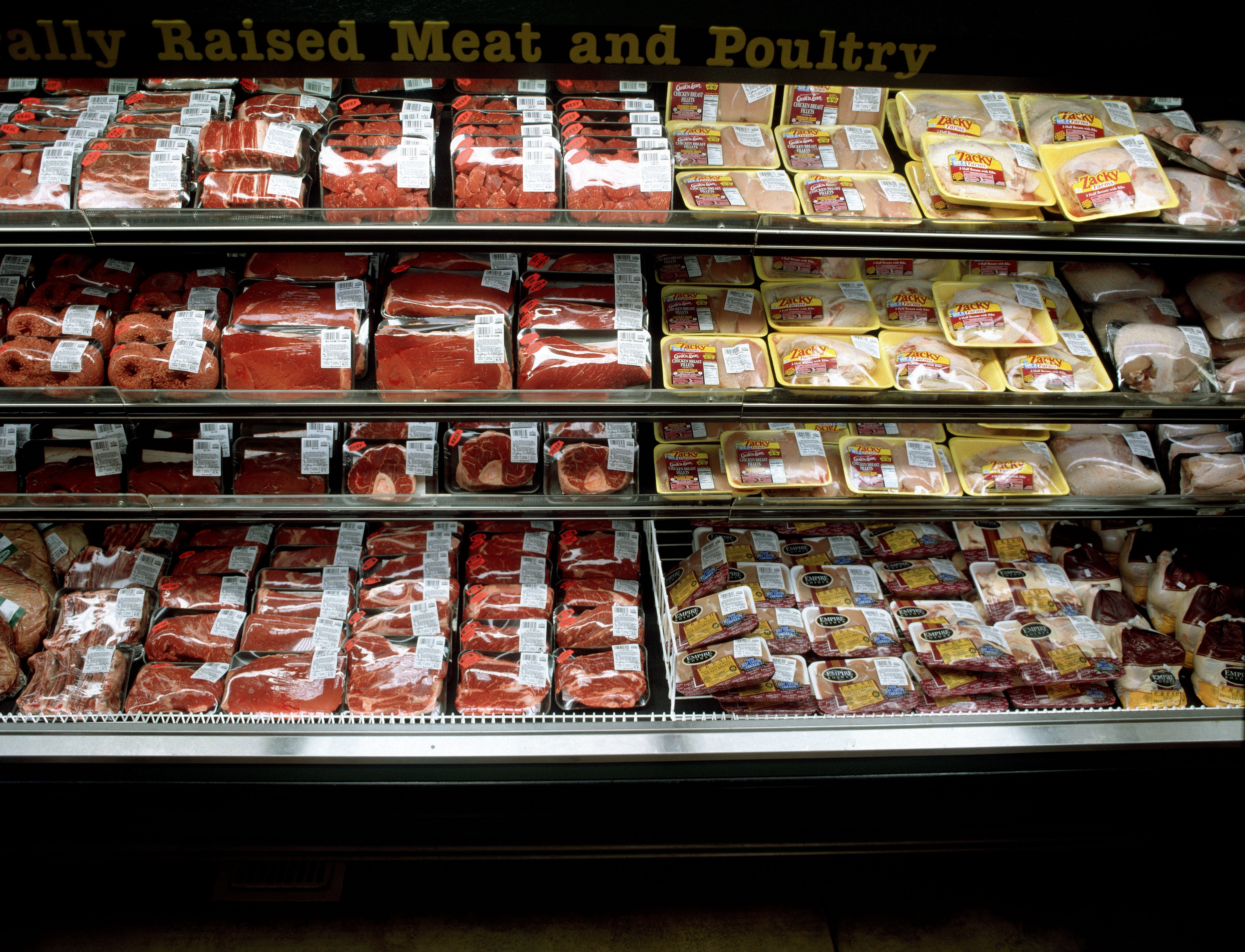 Refrigerated grocery display with packaged meats, including beef and poultry, on multiple shelves