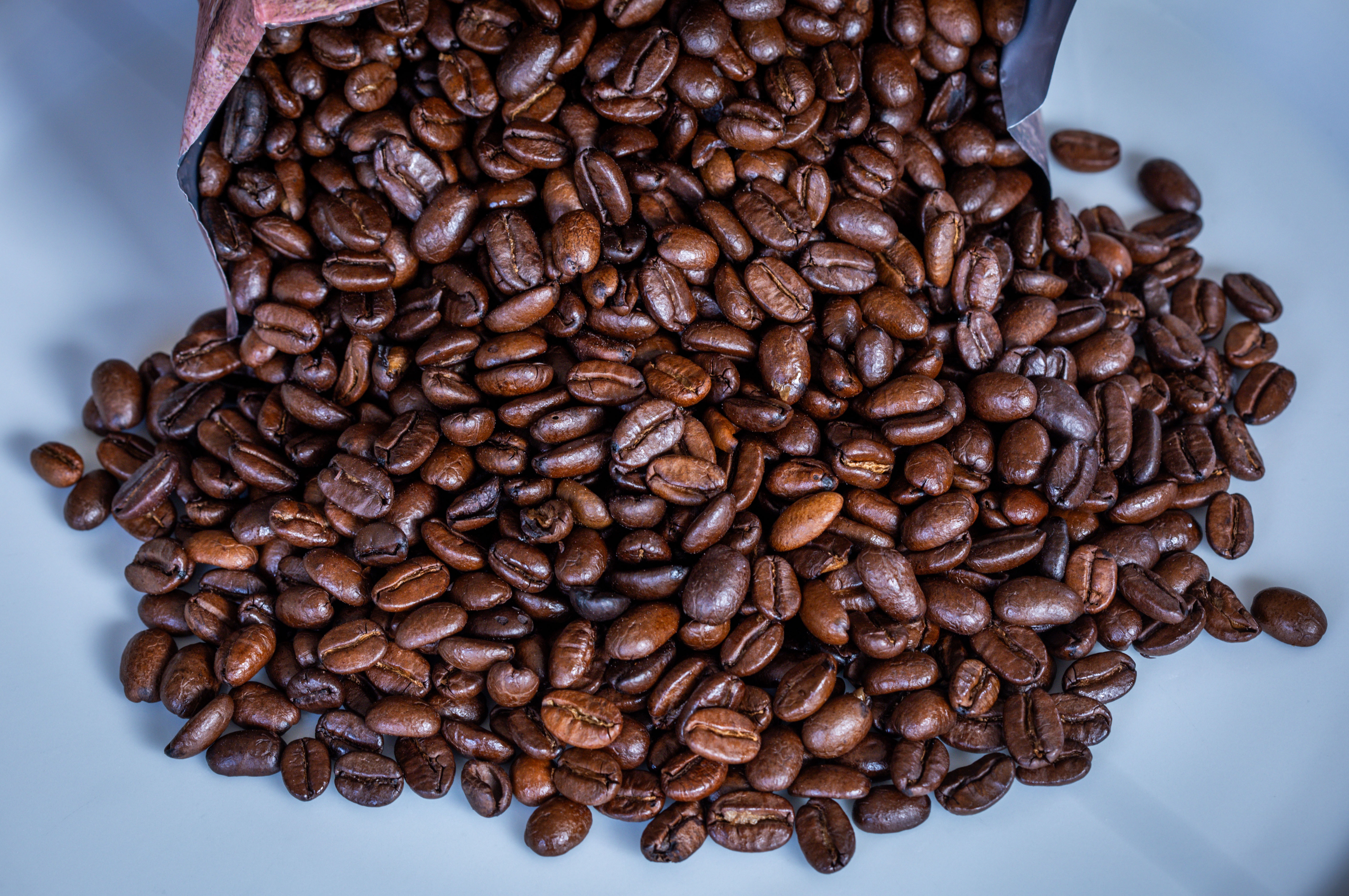 Coffee beans spilling from an open bag onto a white surface