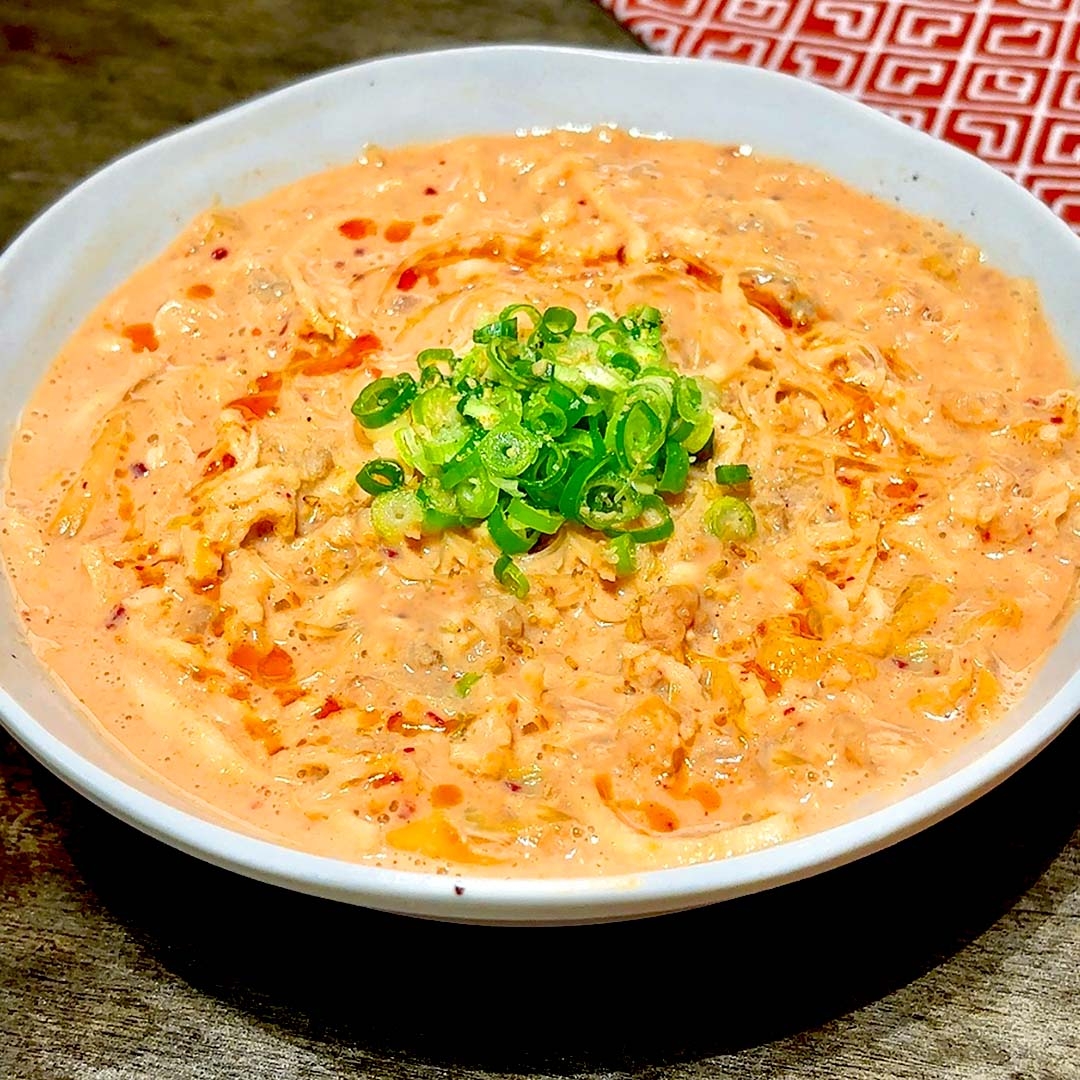 クリーミーなスープにネギをトッピングした一皿の料理。