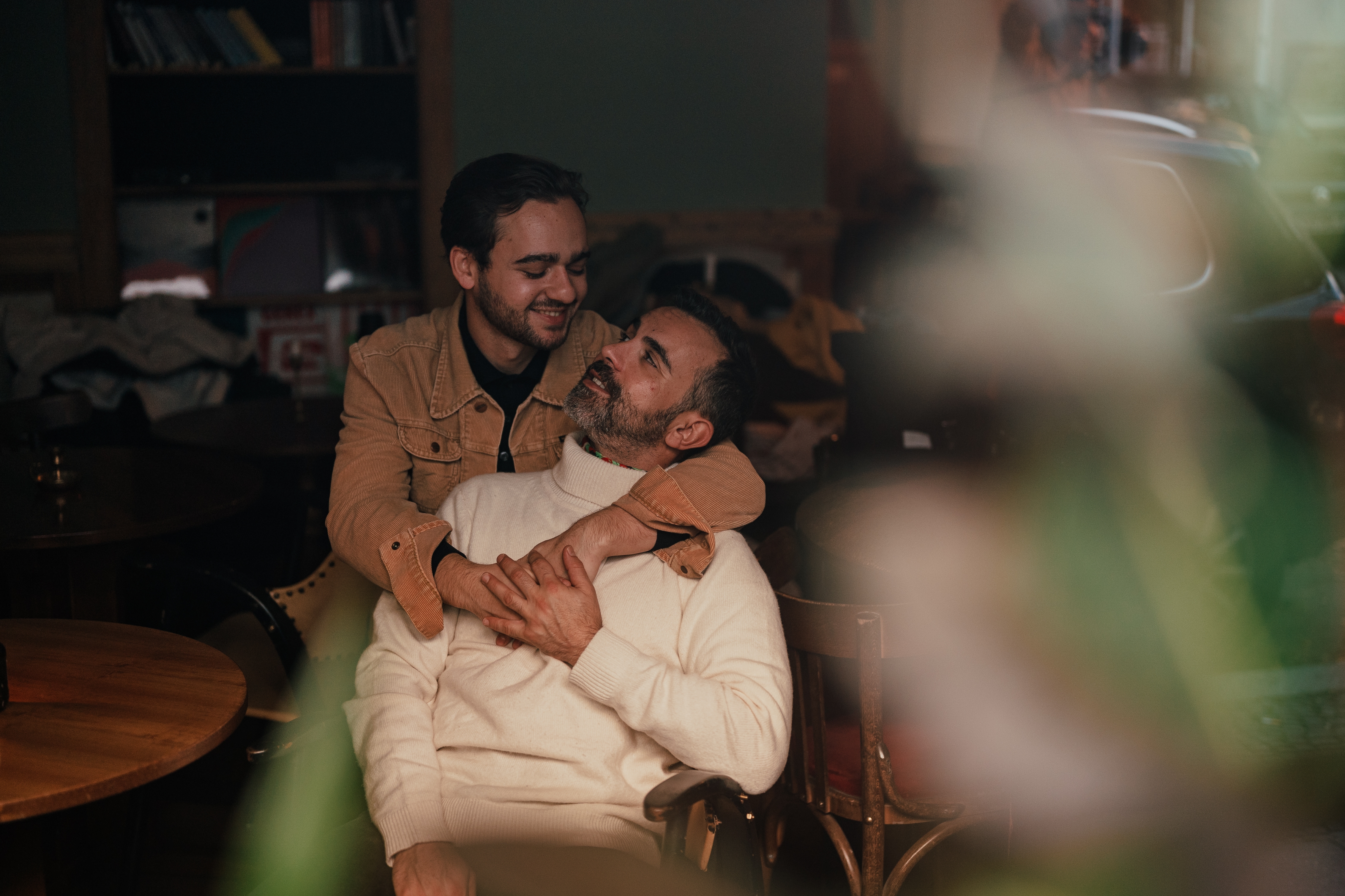 Two people in a cozy moment, embracing and smiling at each other in a warmly lit room