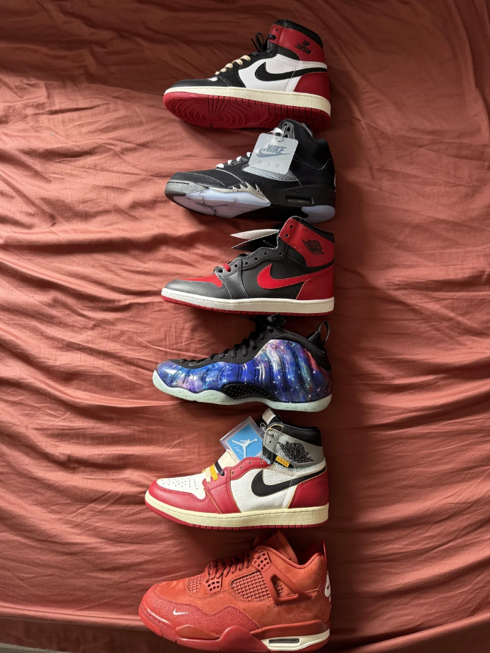 Six different pairs of Nike sneakers arranged in a vertical line on a bed, showcasing various designs and styles