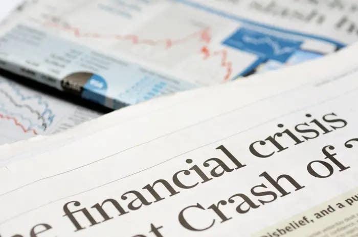 Newspaper headline discusses the financial crisis, with graphs and charts visible in the background, indicating economic analysis