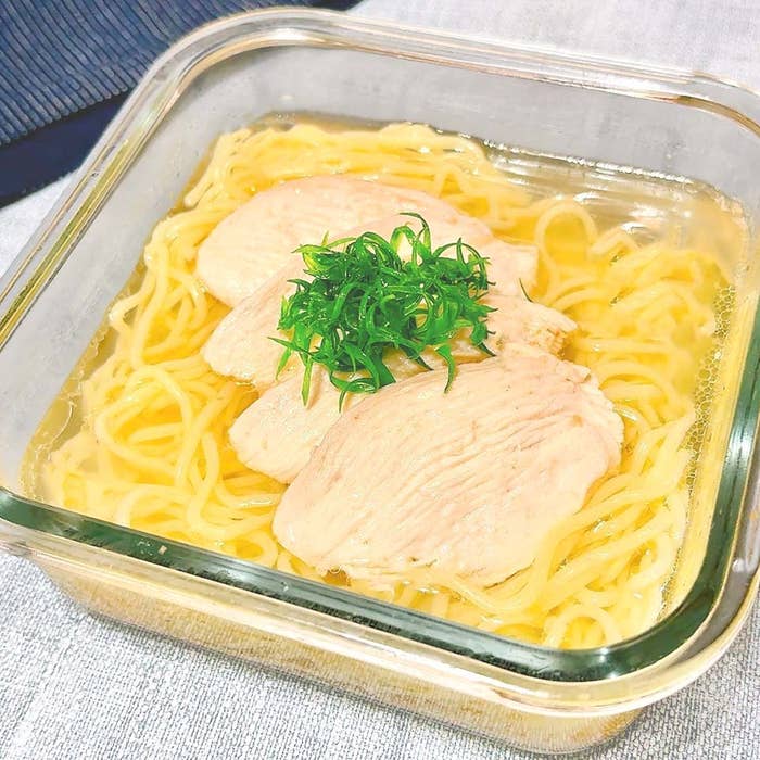 ガラス容器に盛られたラーメン。スープに浸した麺と、薄切りの鶏肉、上に刻んだ青ネギがトッピングされている。
