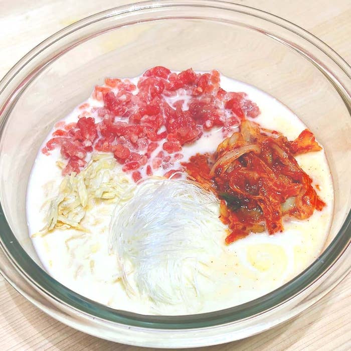 ガラスボウルに刻んだ肉、キムチ、春雨、液体が入っている。調理の準備中の様子。