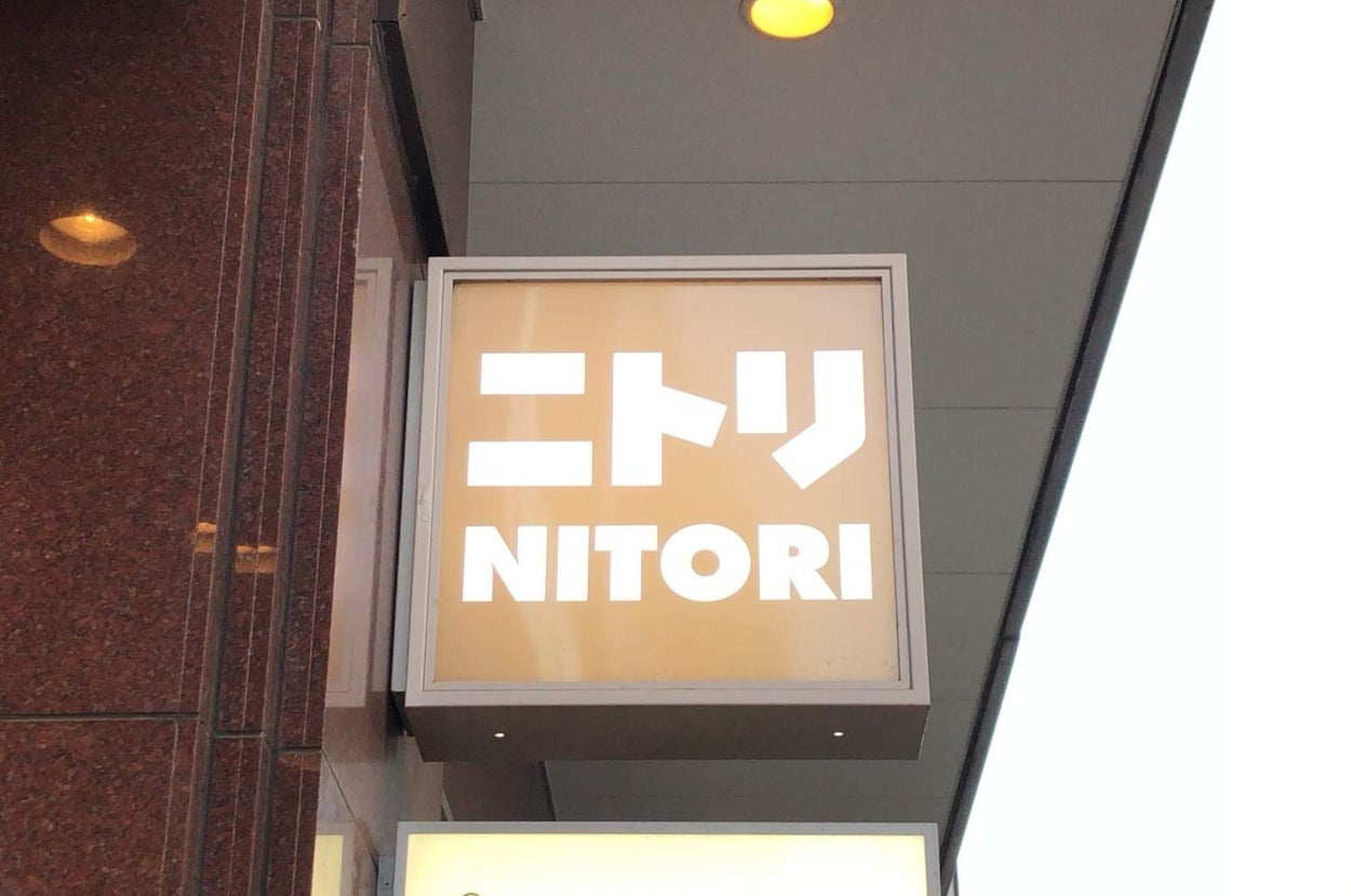 建物の外にある「ニトリ」のロゴを表示する看板。
