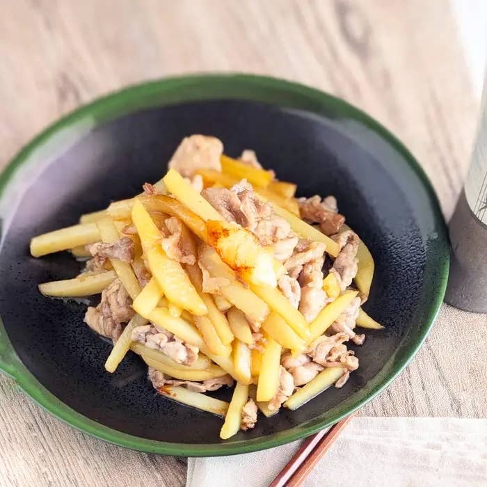 細切りポテトと肉の炒め物が黒い皿に盛られている料理。