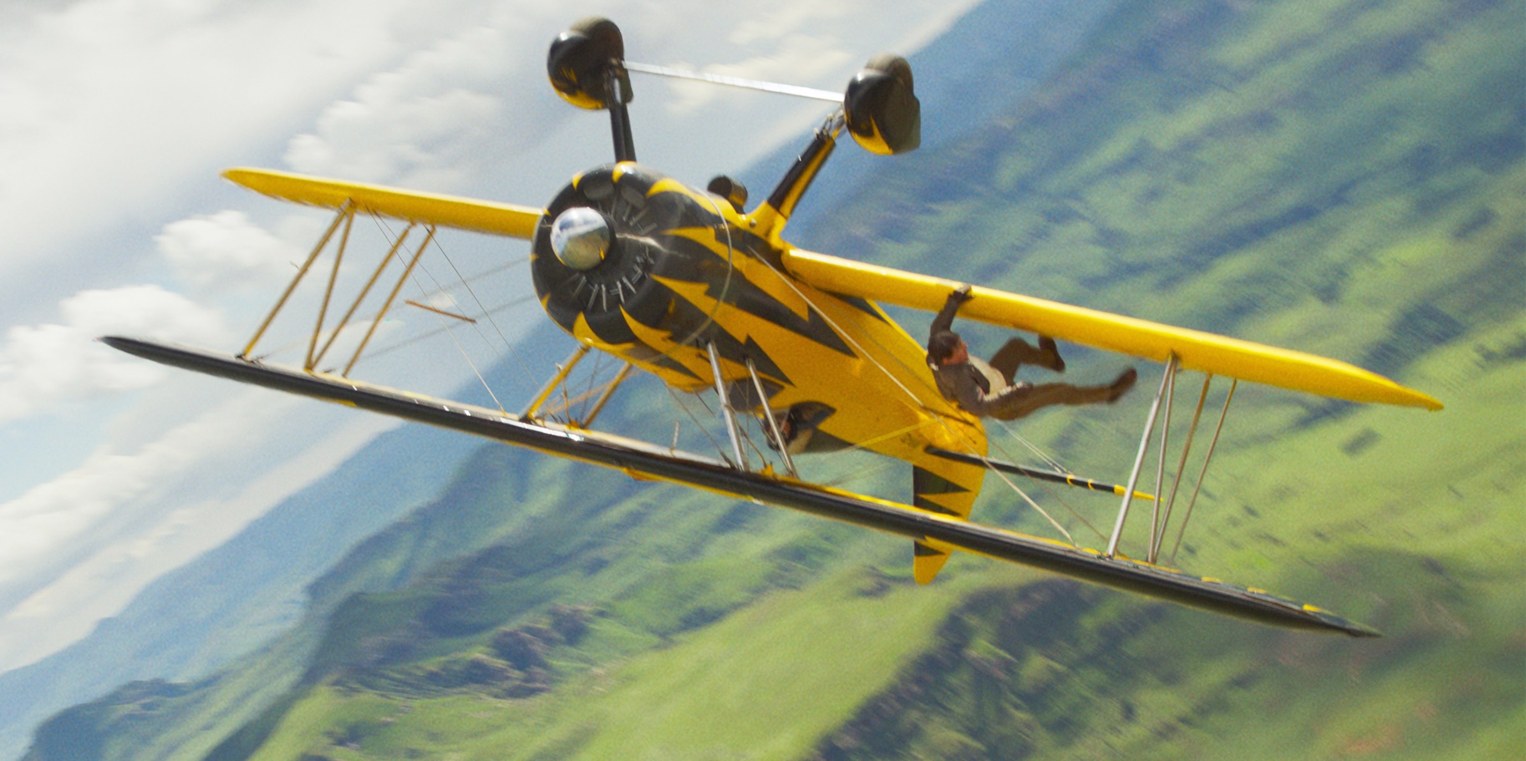 Tom Cruise as Ethan Hunt hanging from the wing of a plane
