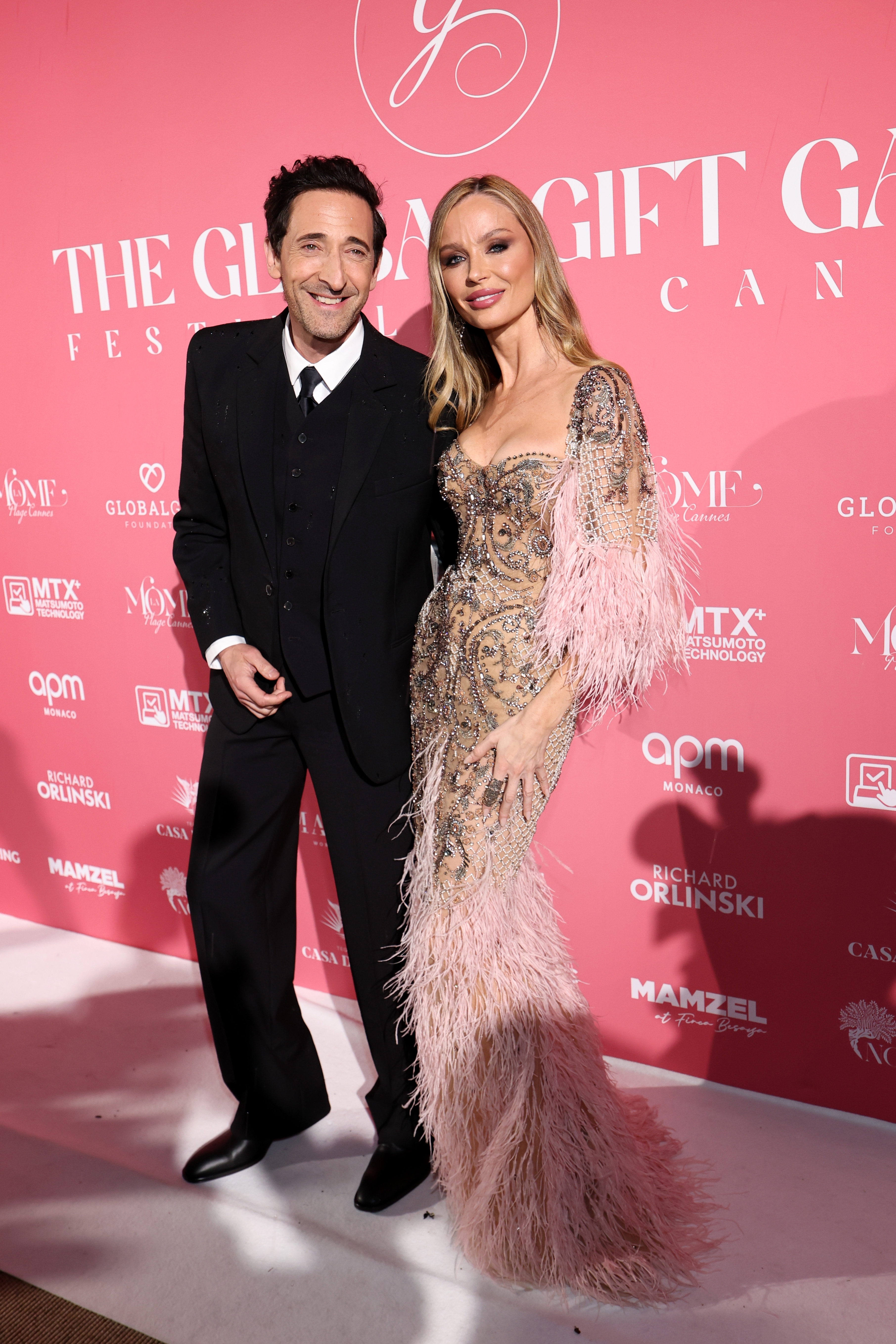 Adrien Brody in a tuxedo, and Georgina Chapman in a detailed gown with feathered accents