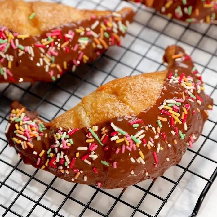 チョコレートとカラフルなスプリンクルでデコレーションされたクロワッサンがクッキングラック上に置かれている。