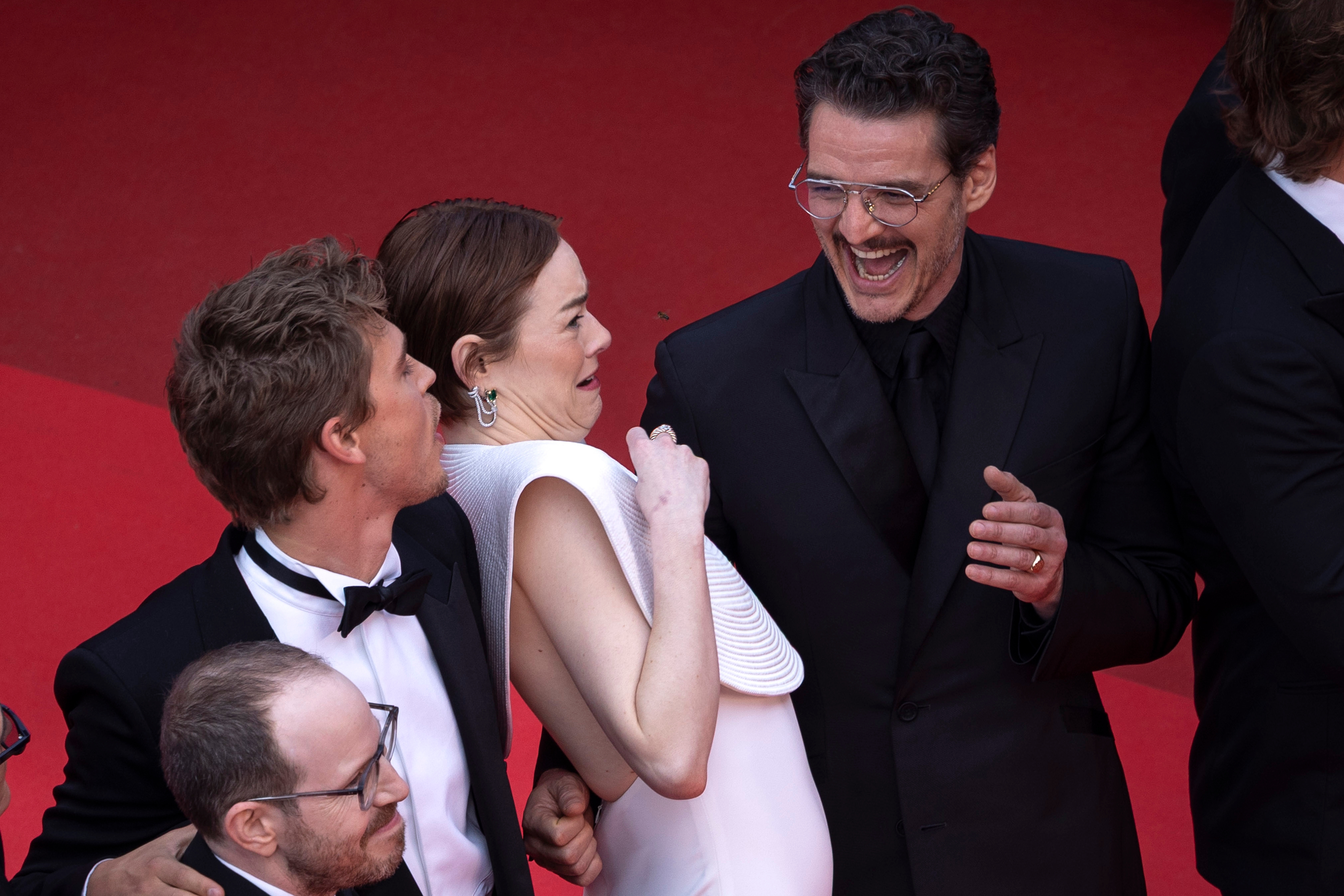Emma Stone shrieks and leans away from a bee on the Cannes red carpet while Pedro Pascal laughs and Austin Butler looks over curiously