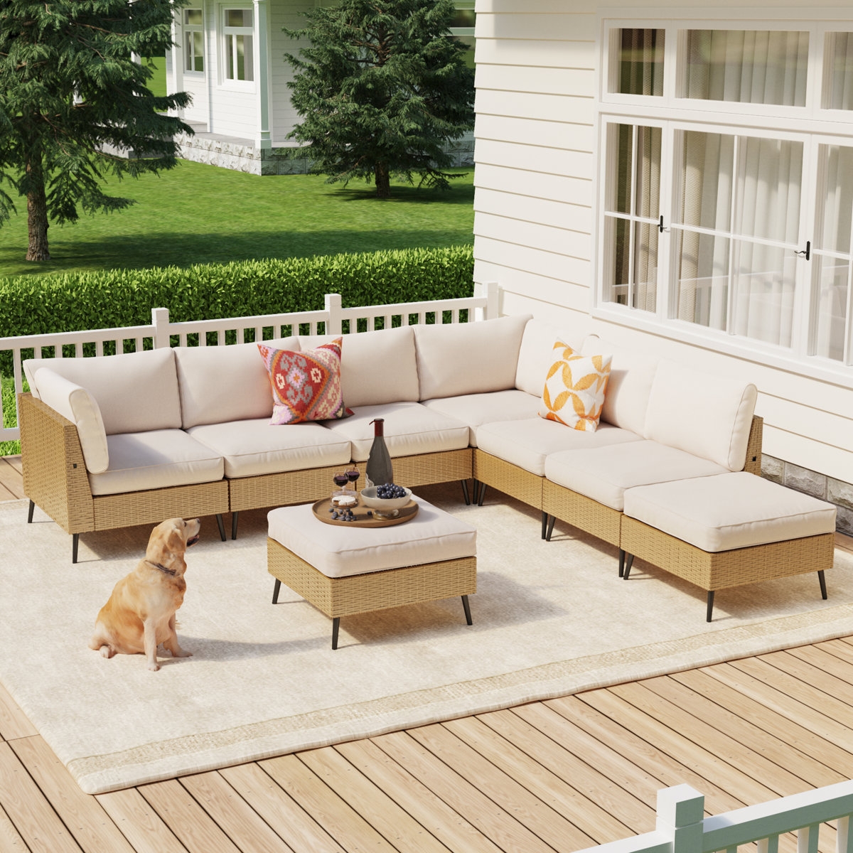 Outdoor patio with beige sectional sofa and patterned cushions, set on a wooden deck. A small table holds a tray and decorative items. A dog sits nearby