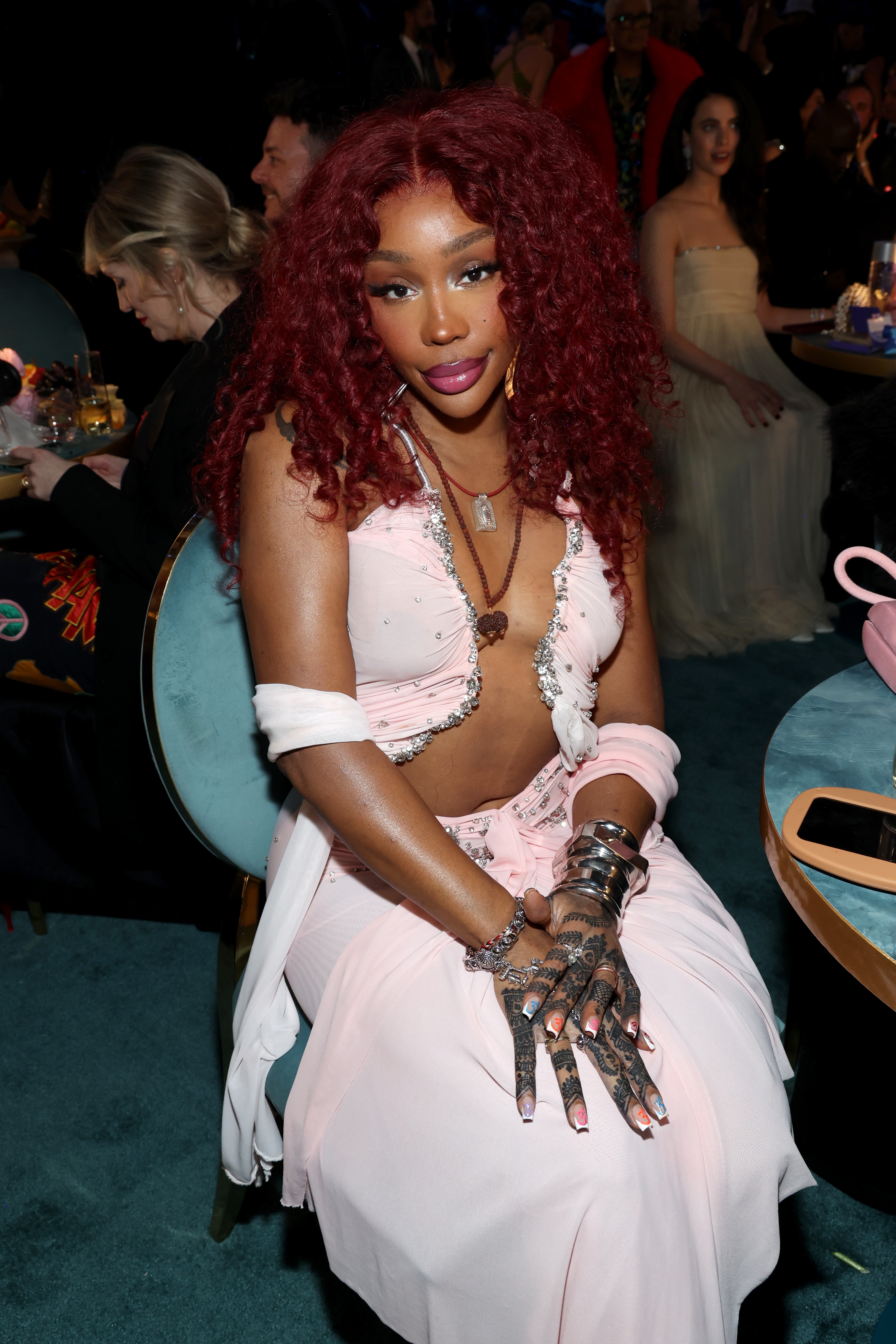 I don’t know who this is, but the person sits stylishly in an elegant gown with intricate hand jewelry at a formal event