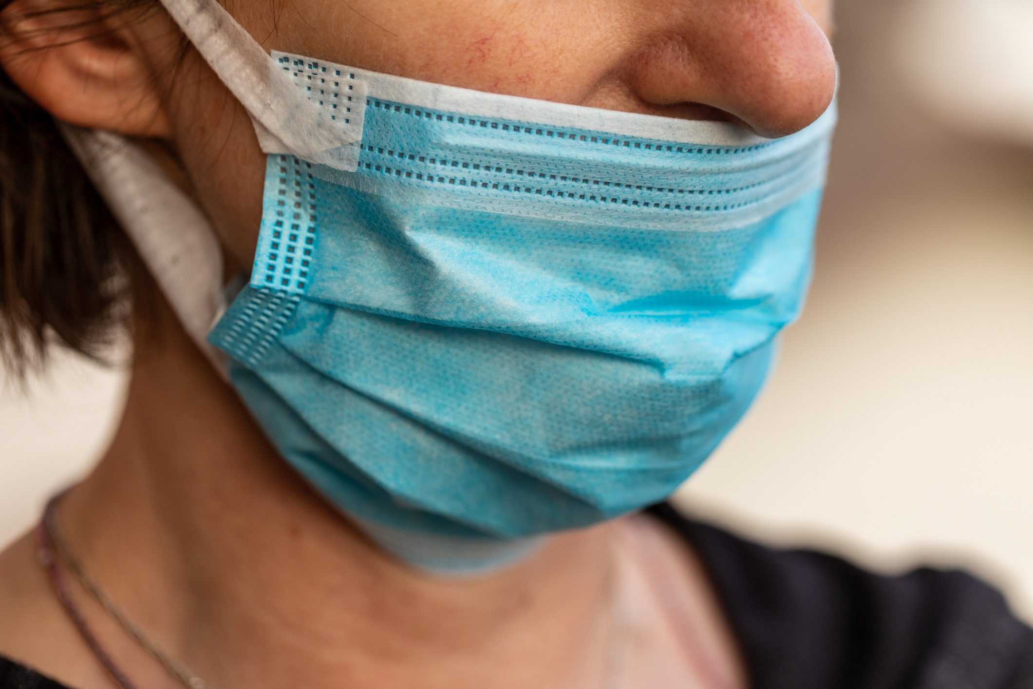 Person wearing a surgical mask covering their nose and mouth, focusing on the importance of mask-wearing for health and safety