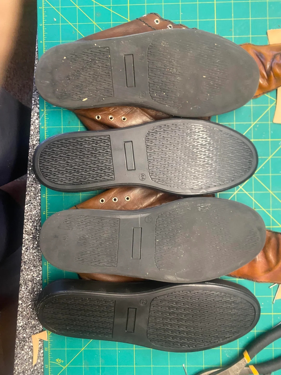 Three pairs of shoes with rubber soles are displayed on a workbench, suggesting a focus on craftsmanship or shoe repair