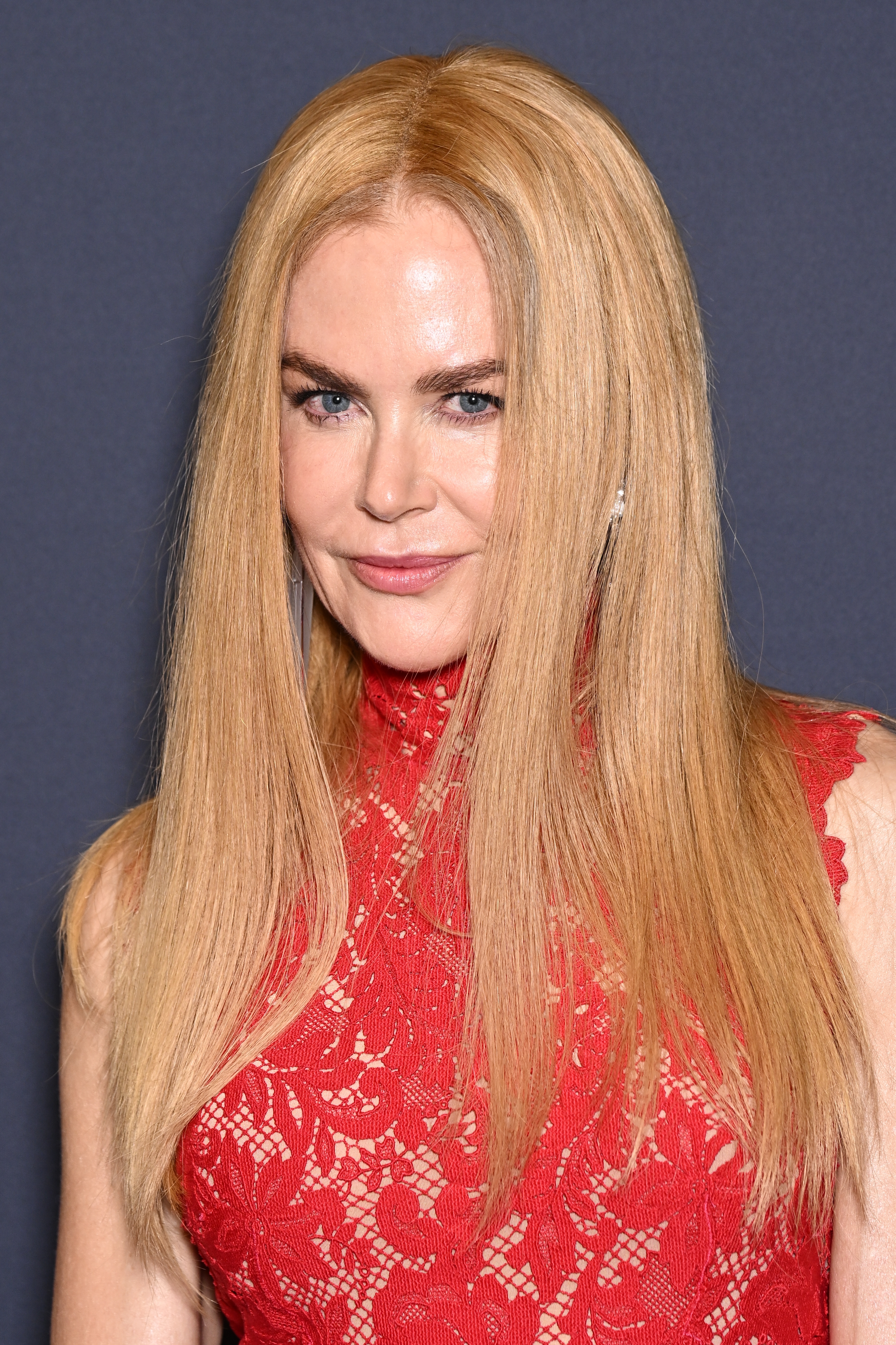 Nicole Kidman with long, straight hair wears a high-neck, sleeveless lace dress