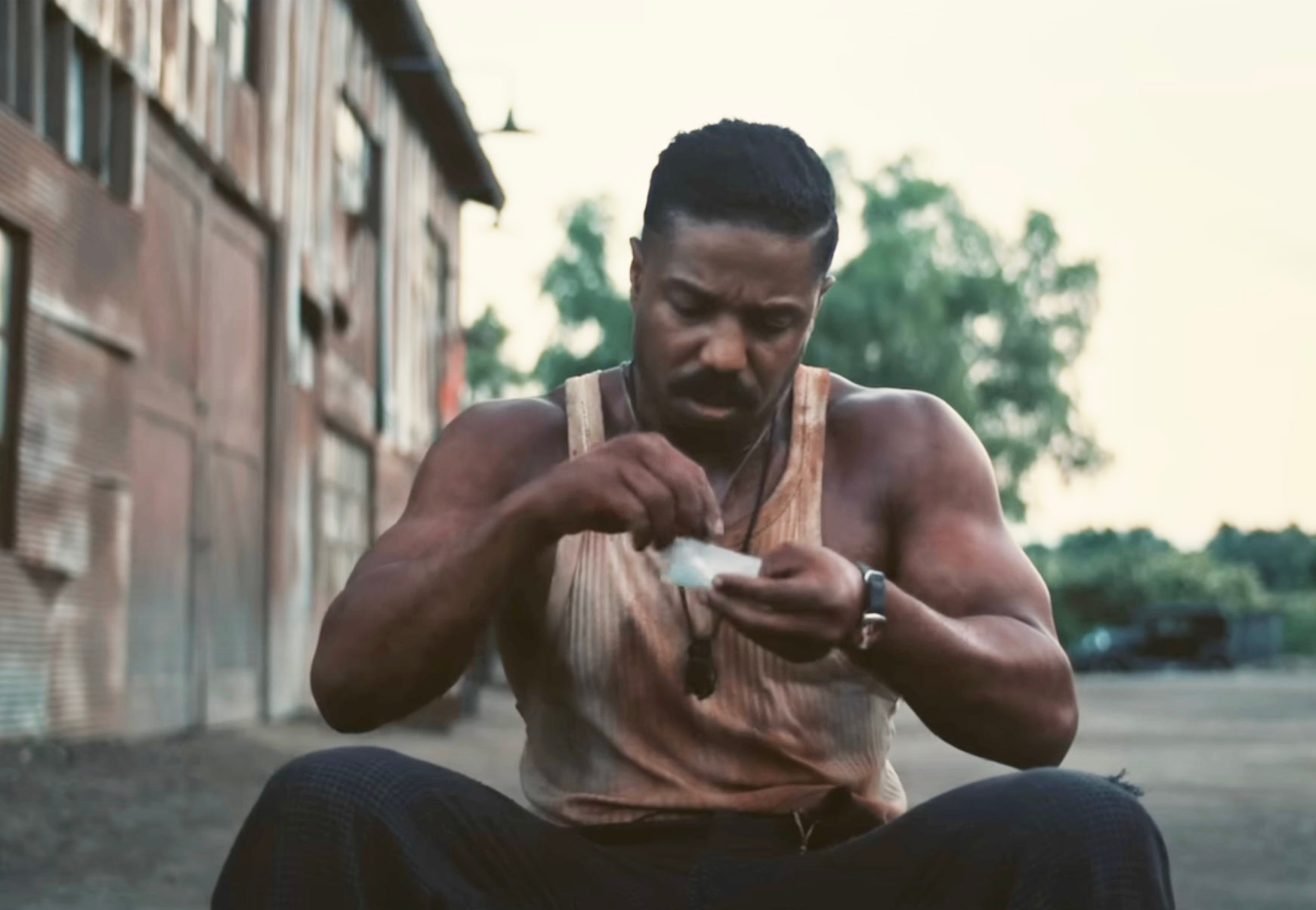 Smoke wearing a bloody tanktop and trying to roll a cigarette