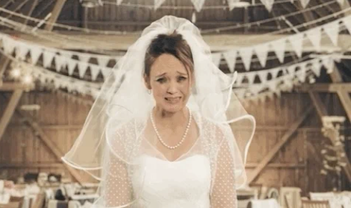 Bride in lace dress and veil looks overwhelmed in decorated wedding venue