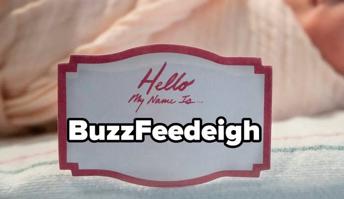 Newborn baby sleeps swaddled in a hospital bassinet with a blank name tag displayed in the foreground