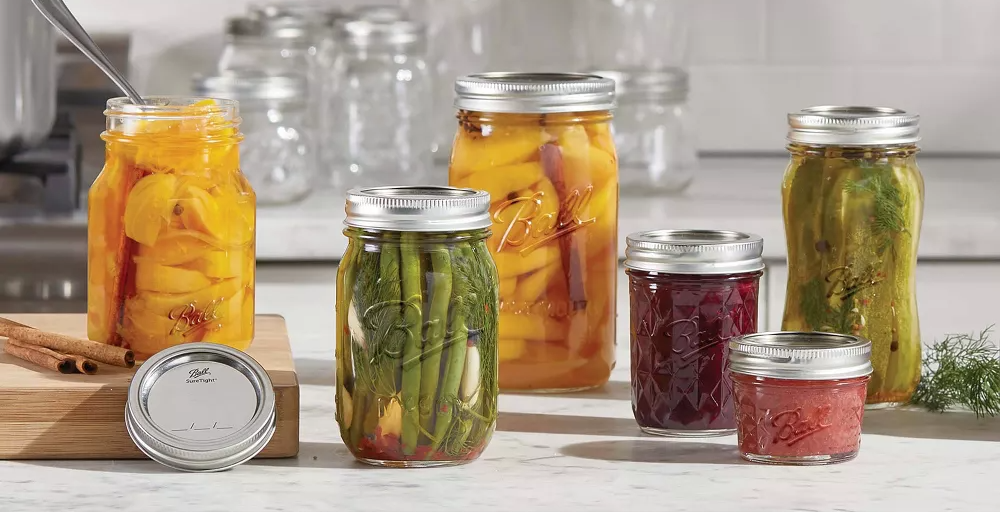 Mason jars filled with preserved foods on a kitchen counter with text: "#1 Most Trusted Mason Jar Brand. Preserve with Confidence - Lock In the Perfect Seal."