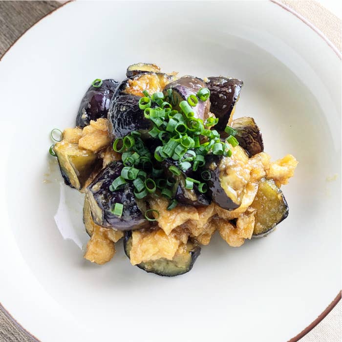 器に盛られたナスとネギがトッピングされた料理。