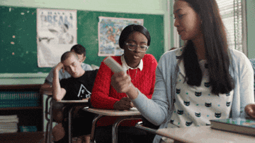 Student in classroom passes note to classmate while others focus on their work