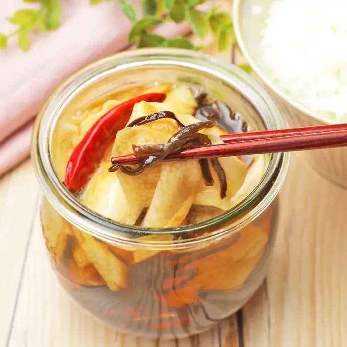 ガラスの瓶に入った長芋の漬物を箸でつまんでいる様子。