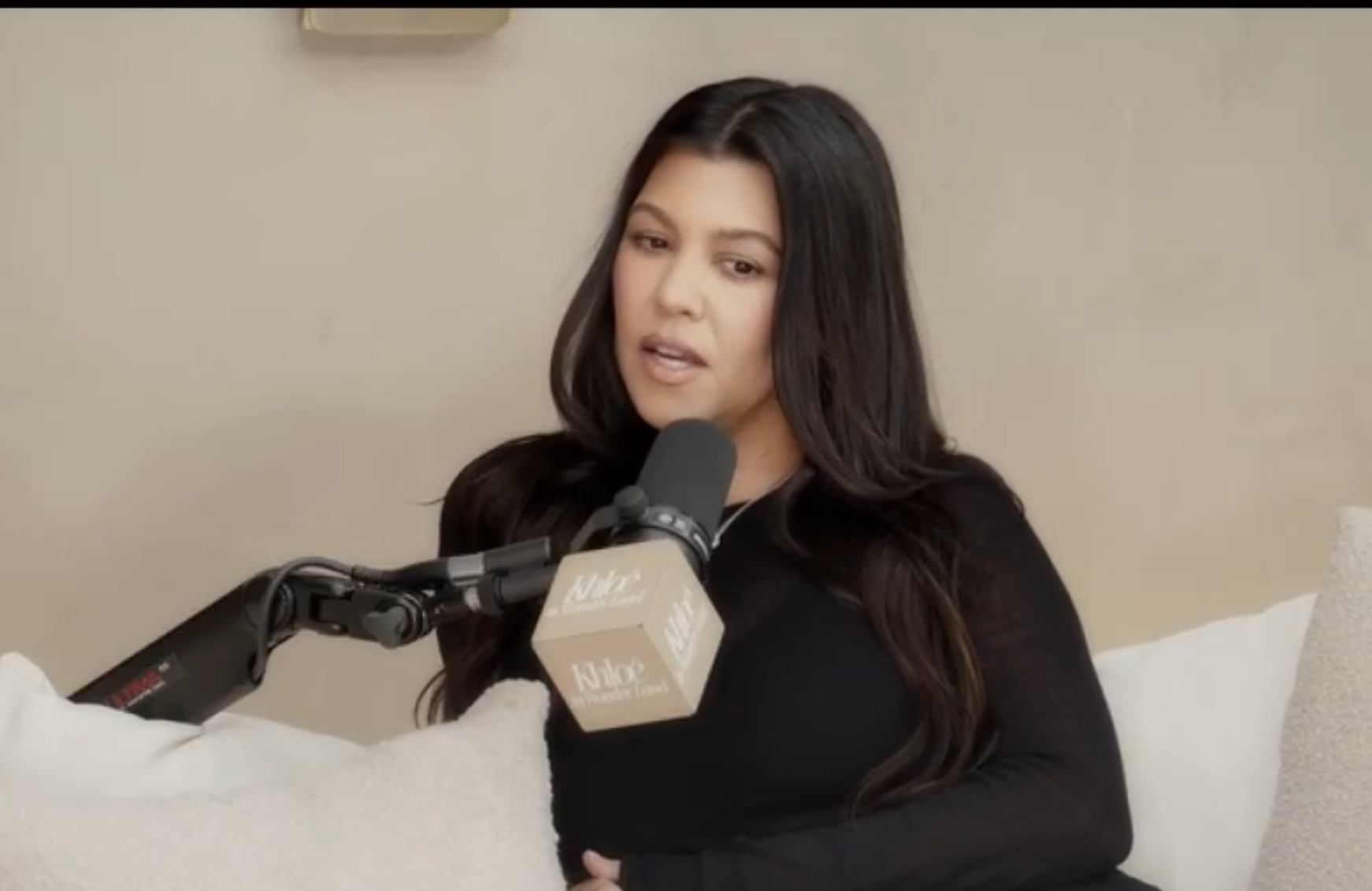 Kourtney Kardashian speaking into a microphone during a podcast