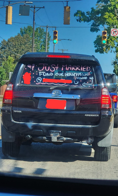 SUV with "Just Married" and "Fund Our Honeymoon" written on the back, decorated with drawings