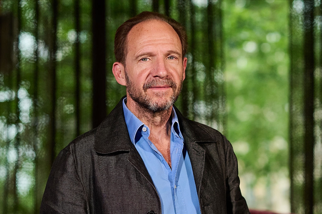Ralph wearing a casual, open-collared shirt and blazer stands in front of a natural, blurred background