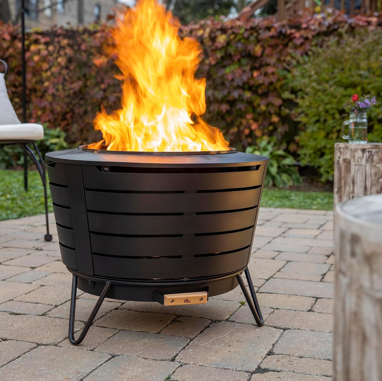A modern   outdoor occurrence  pit with a sleek achromatic  design, placed connected  a patio. Flames are visibly rising from it, hinting astatine  warmth and ambiance