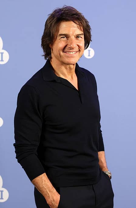 Person in a black sweater and pants poses in front of a BFI backdrop, smiling with hands in pockets