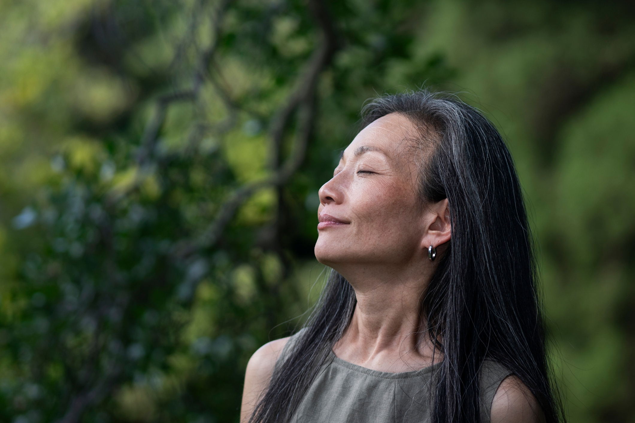A person peacefully enjoying nature with eyes closed, standing outdoors