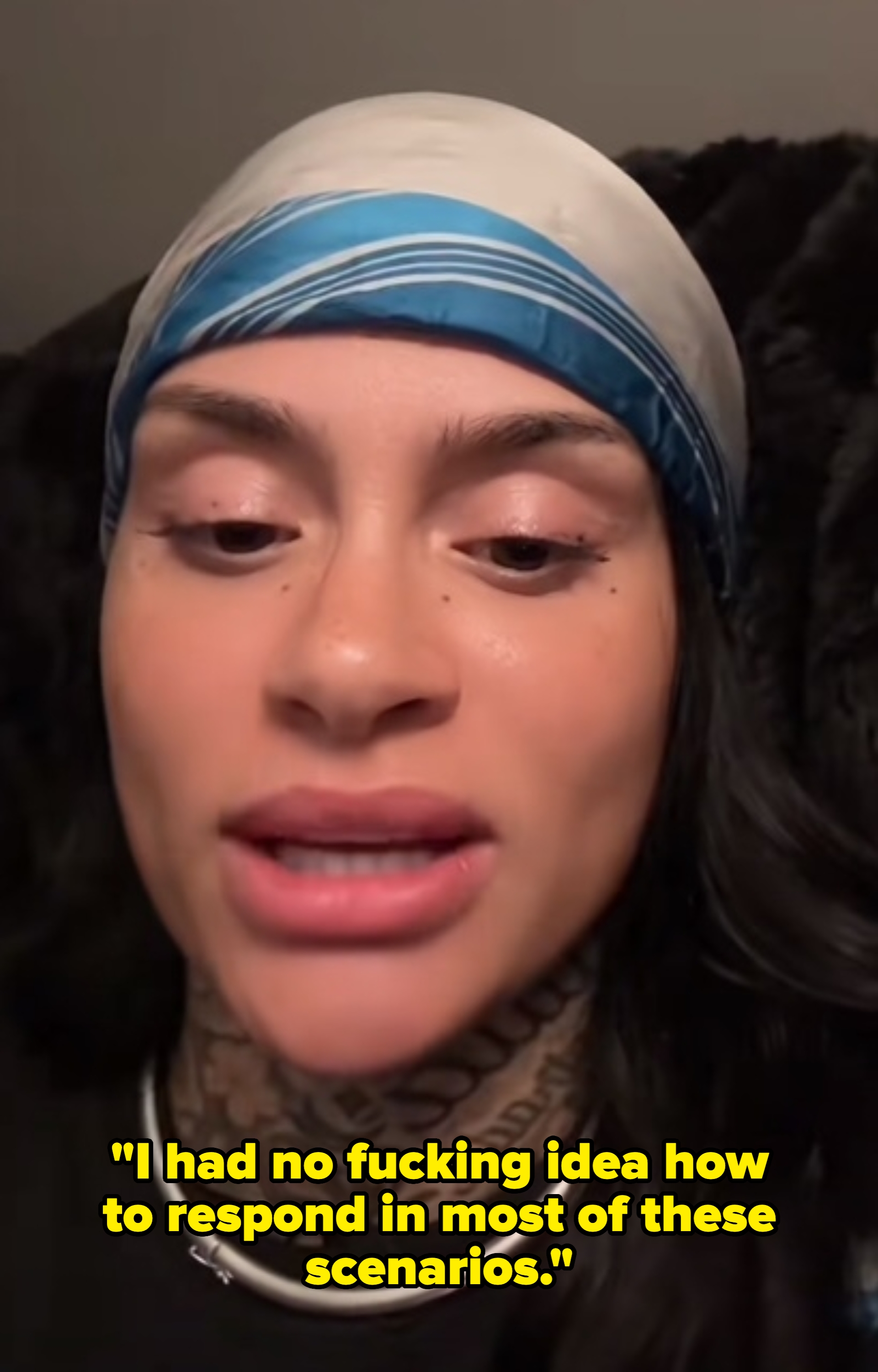 Kehlani wearing a headscarf, top, and a silver necklace, with visible tattoos on the neck, looking directly at the camera