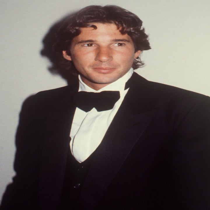 Man in a tuxedo with a bow tie posing against a plain background
