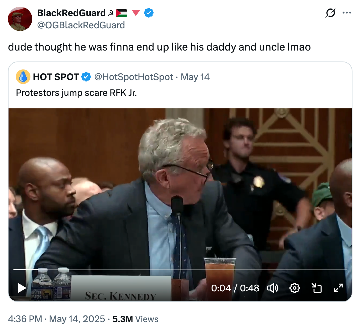 A tweet with a screenshot of a video showing a man seated in a formal setting, labeled "Sec. Kennedy," with a police officer in the background