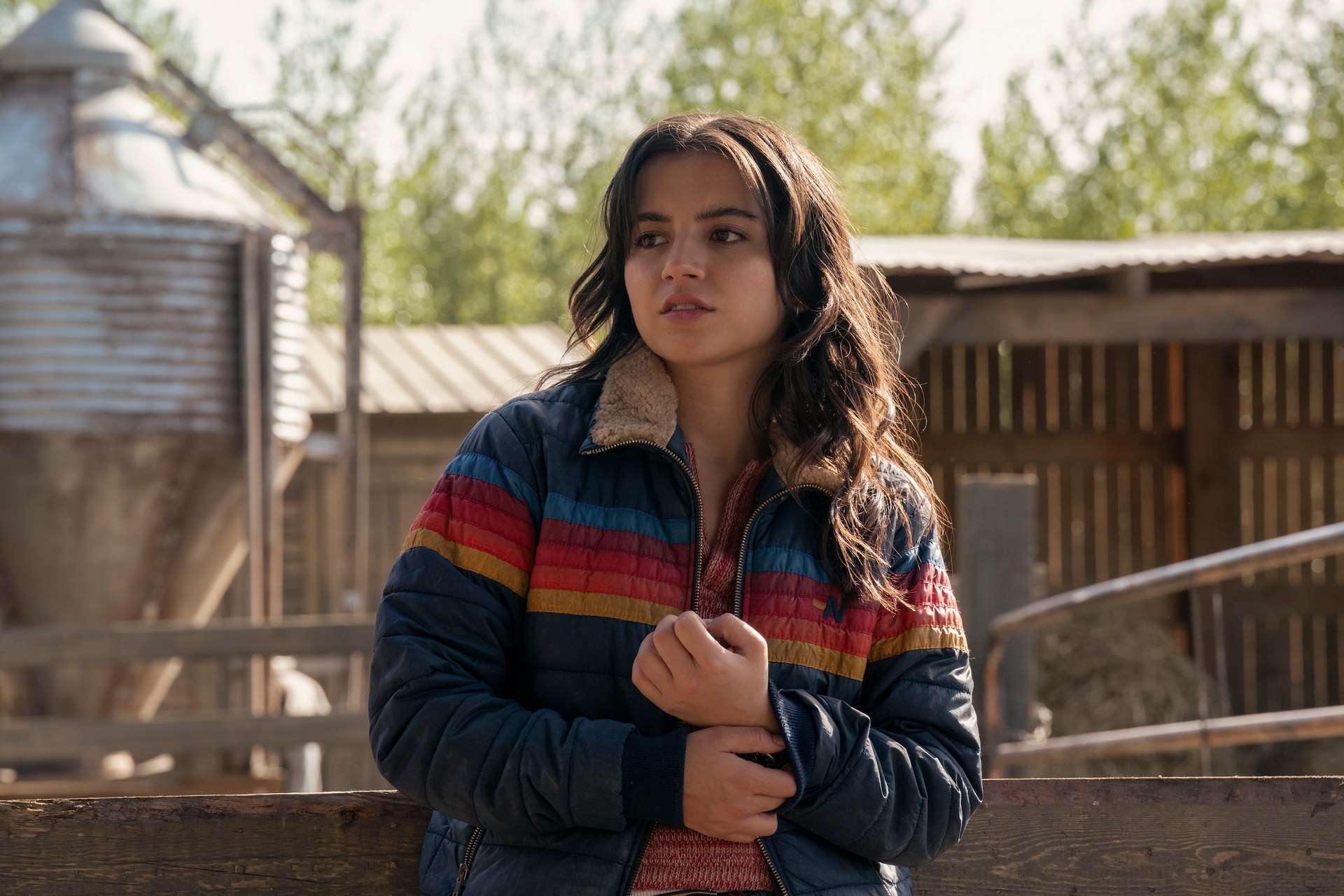 Dina in a striped jacket stands pensively outside