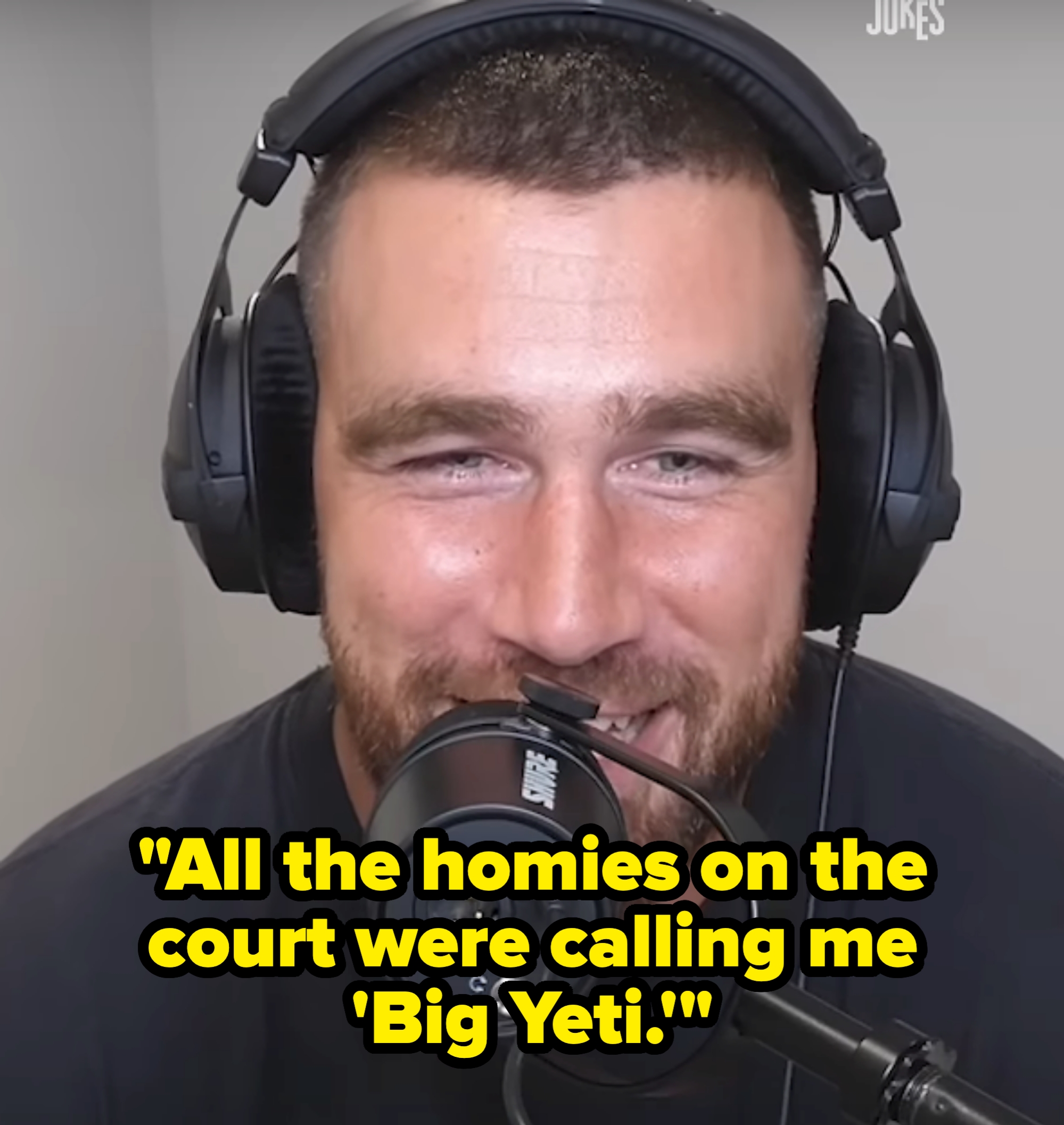 A person wearing headphones speaks into a microphone during a podcast or recording session