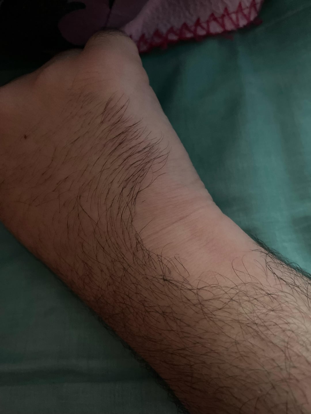 Close-up of a person's wrist and forearm, showing hair and light shadowing