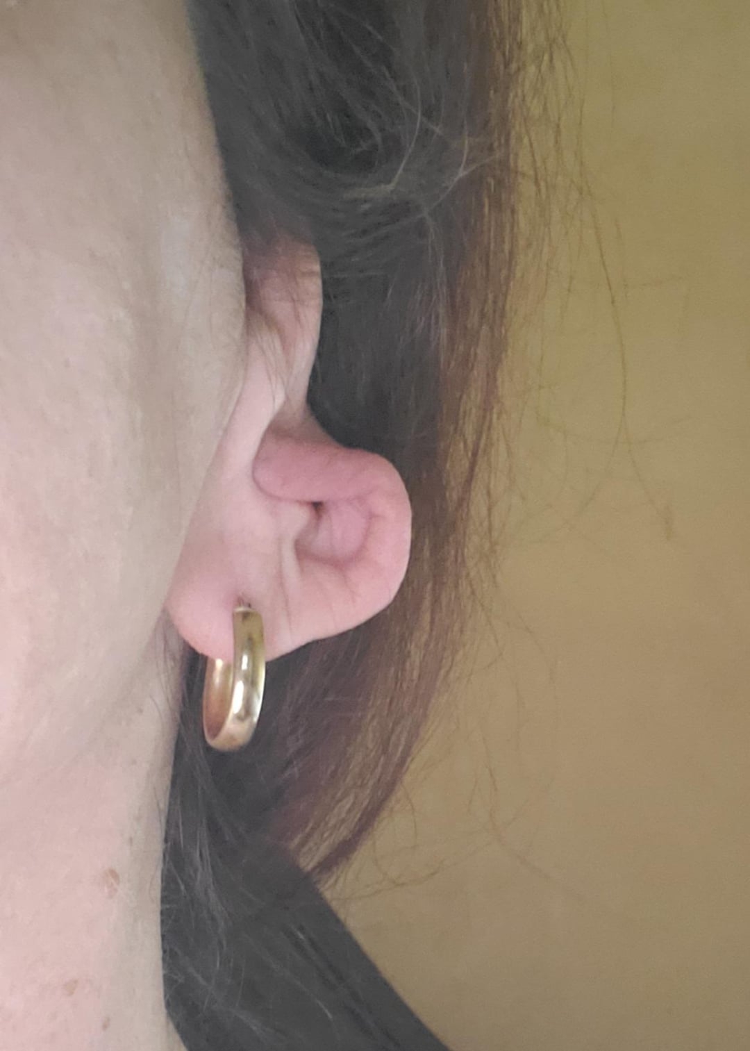 Close-up of a person's ear showing a gold hoop earring