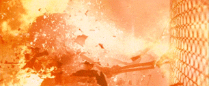 Intense fire explosion near a chain-link fence, with debris flying through the air
