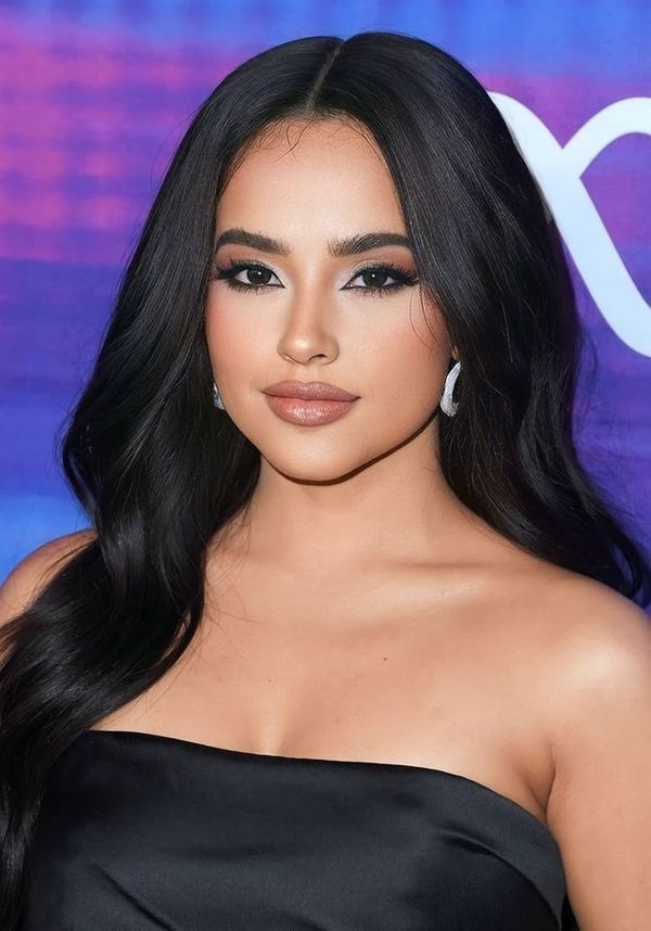 Persona con cabello largo en un evento, luciendo un elegante vestido sin tirantes