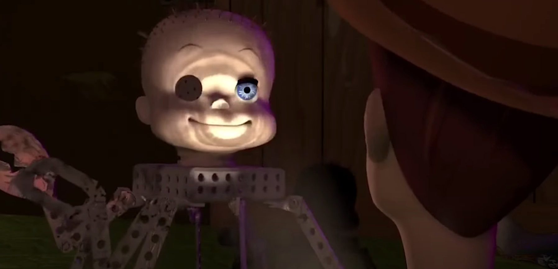 Toy with robotic spider legs and doll head, featuring a wide smile, interacts with a person wearing a hat in a dimly lit scene