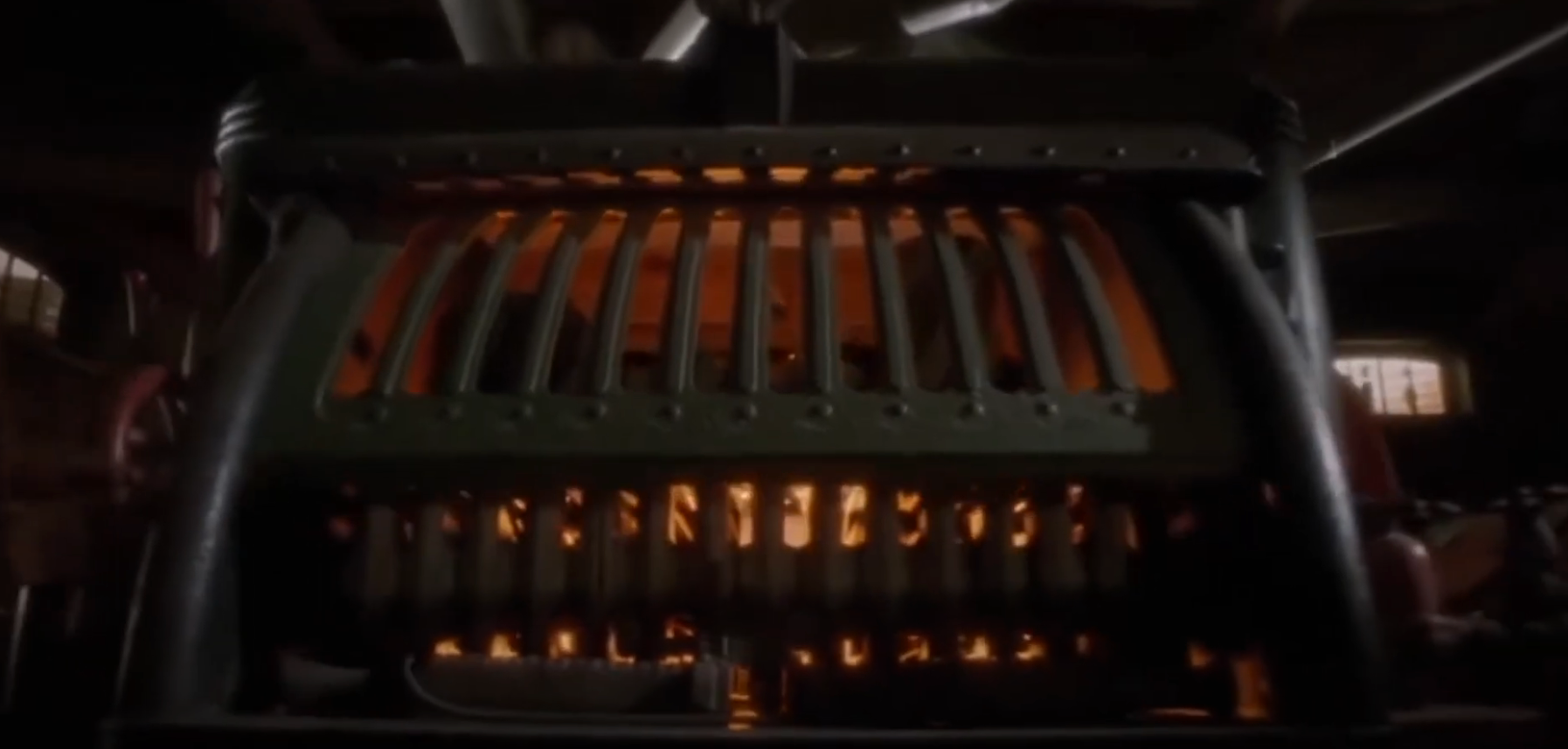 View of a vintage typewriter from behind, with glowing orange light visible through its keys. 