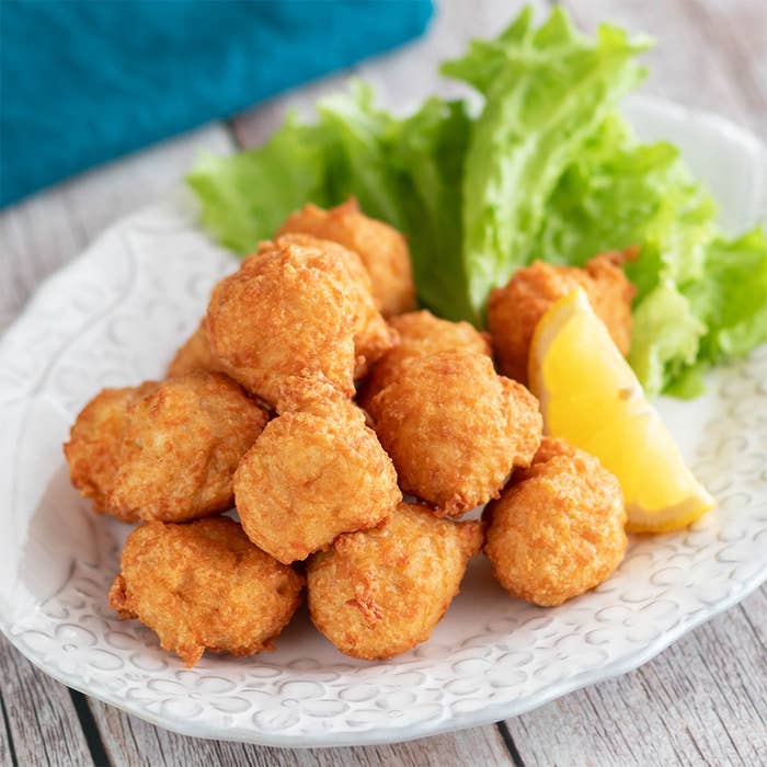 白い皿に盛られたフライドチキンナゲットとレタス、レモンのスライス。