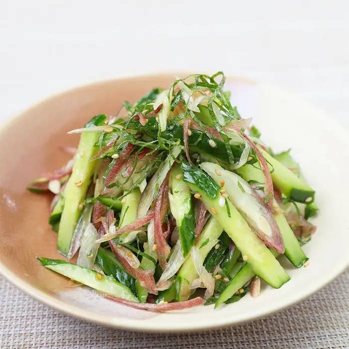 きゅうりと野菜のサラダが皿に盛られている。爽やかな見た目でゴマがトッピングされている。