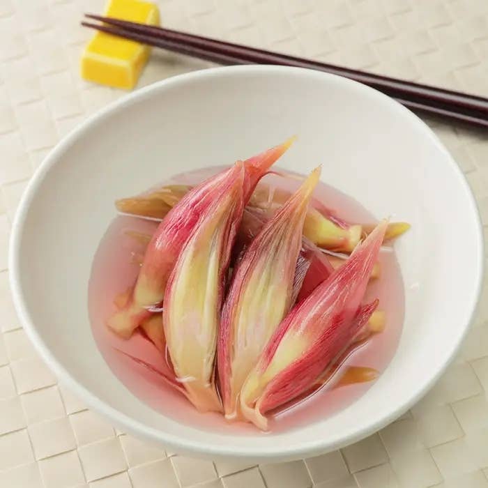 白い皿に盛られたみょうがの酢漬けが並び、隣には箸が置かれています。